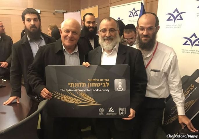 Israel's Welfare and Social Services Minister Haim Katz, left, holds a display card with Rabbi Mendy Blau, director of Colel Chabad’s Israel programs, at the Knesset for the launch of a major food-security initiative. (Photo: Welfare and Social Services Ministry)