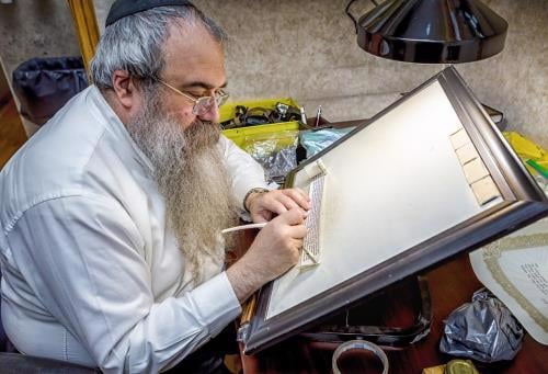 A trained scribe inspects a tefillin scroll (Photo: Eliyahu Parypa)