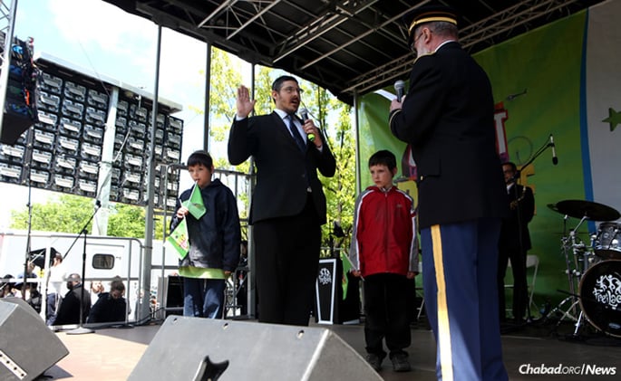 Rabb Yossi Madvig, left, “solemnly affirmed” his commitment to the U.S. Army Reserve as a new chaplain on May 14 in Brooklyn, N.Y. Presiding over the ceremony was U.S. Army Col. (ret.) Jacob Goldstein. Two of Madvig's children joined him onstage: Menachem Mendel, left, and Levi Yitzchok.