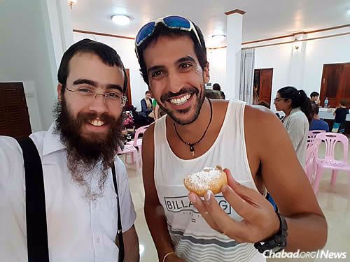The rabbi and a new friend enjoy a jelly doughnut (homemade, of course) at Chanukah.