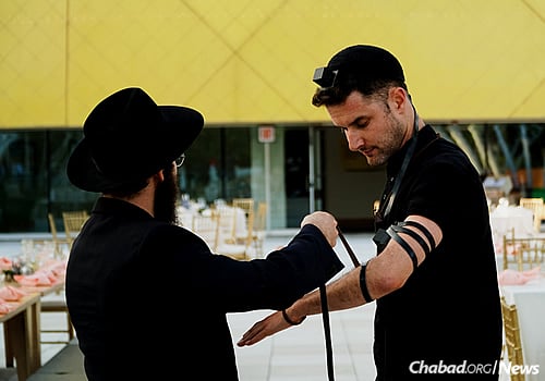 Local yeshivah students help guests don tefillin. (Photo: Avraham Edery)