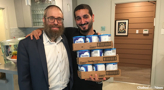 Rabbi Chaim Lazaroff, left, co-director of Chabad of Uptown, hands containers of baby formula to a father in Houston. Chabad-Lubavitch Texas Regional Headquarters has been coordinating rescue and relief efforts since the start of Hurricane Harvey.