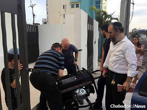 Providing generators to assist community members, overseen by Rabbi Zarchi, at right.