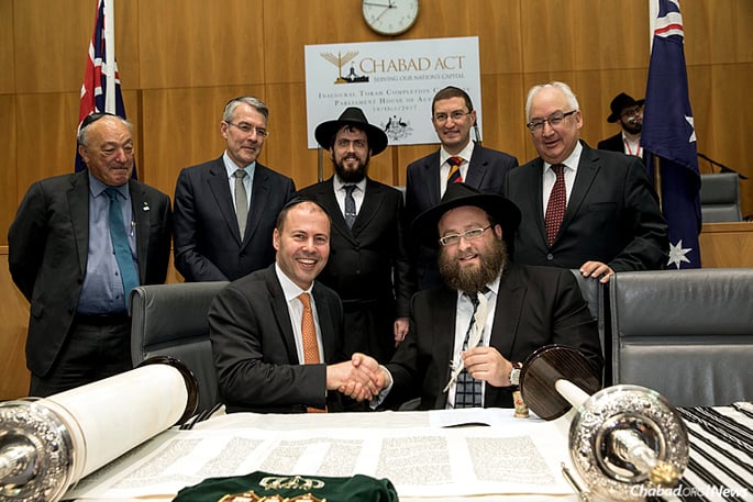 Rabbi Eli Gutnick, right, finishes the final letter of a new Torah in the Canberra Parliament House, witnessed by The Hon. Josh Frydenberg, MP, seated next to him. Standing, from left, are Dr. Mike Freelander, MP; The Hon. Mark Dreyfus, MP; Rabbi Shmueli Feldman, co-director of Chabad ACT in Canberra; Julian Leeser, MP; and the Hon. Michael Danby, MP. Behind them is Menachem Feldman. (Photo: Andrew Taylor)