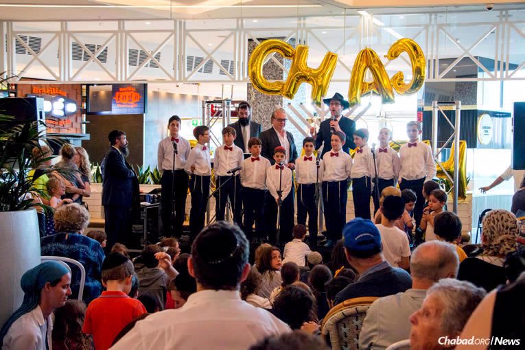 Chabad Rabbi Levi Wolf leads a boys choir at the menorah-lighting organized by The Central Synagogue at the Westfield Bondi Junction shopping center in Sydney, Australia, on Tuesday, Dec. 12, the first night of the eight-day holiday of Chanukah. (Photo: Alon Bar David)