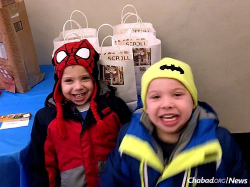 Four-year-old twins Joshua and Mason Weitz pick bags up on Fridays at Kiddie Korner to deliver to area seniors. Inside are soup, challah, cake, Shabbat materials, and sometimes, seasonal items (this month, warm scarves).