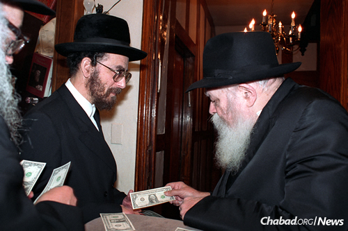 Slonim, left, receives a dollar from the Rebbe. (Photo:JEM/The Living Archive)