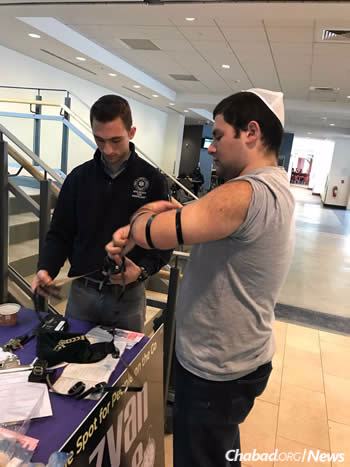 Kevin Brown, right, dons tefillin with Meir Berkman. Brown had not heard of tefillin when he arrived at Binghamton as a freshman, and now as a Jewish student leader helped lead the campus campaign.