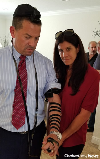 Michael Udine, commissioner of Broward County, puts on tefillin in the Pollack home next to his wife, Stacey.