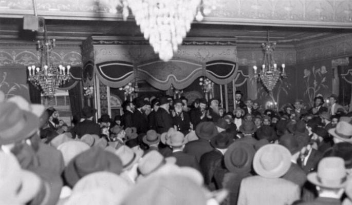 The Rebbe dances and sings in his place at a Yud Tes Kislev gathering held in a rented hall in 1954.
