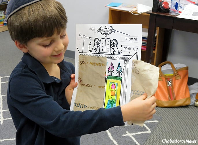 A first-grader displays his project after learning how and where a Torah is kept.