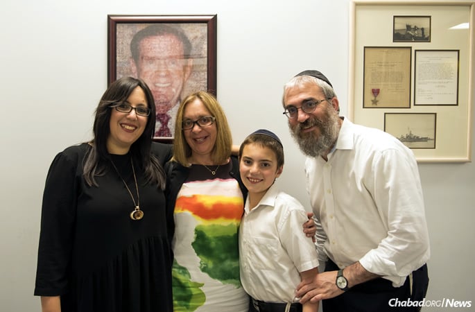 Rabbi Yossi and Miriam Esther Wilhelm, co-directors of Chabad of Knoxville, Tenn., with their oldest child, Mendel. With them is Ann Friedlander, whose mother, Helen Eisenberg, provided seed money for the day school named for Friedlander’s father, Stanford Eisenberg, seen in the framed photo.