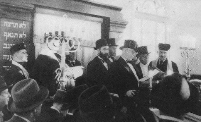  Mordechai Dubin being introduced in a synagogue, possibly during his 1929 visit to the United States. That year he accompanied the sixth Rebbe, Rabbi Yosef Y. Schneersohn, of righteous memory, on the Rebbe's trip to America. At the time, Dubin met with President Herbert Hoover and other American dignitaries, before leaving back to Latvia where he felt his voice was needed in the Saeima.