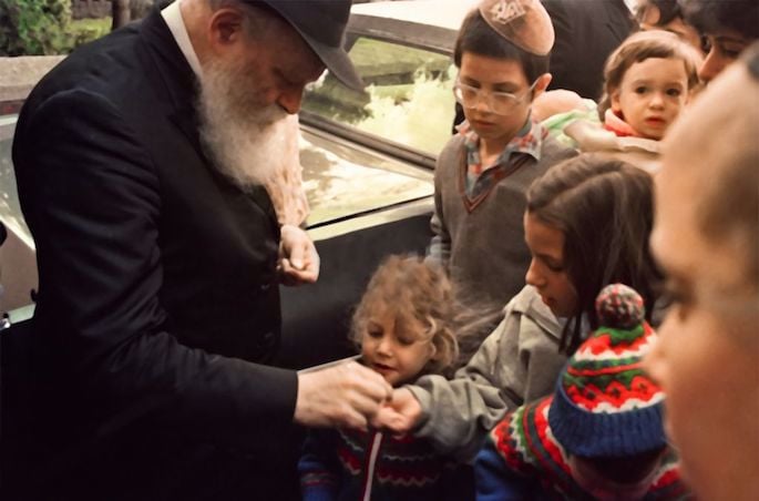 The Rebbe gives a young girl a coin so that she can donate it to charity (1980s).