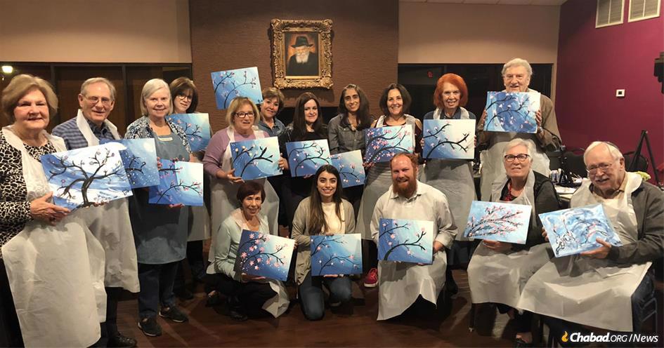 Participants display their artwork at the “Smile on Seniors” program, part of Chabad of Downtown in Phoenix, co-directed by Rabbi Levi Levertov, bottom center, and Chani Levertov, top row, fifth from right.