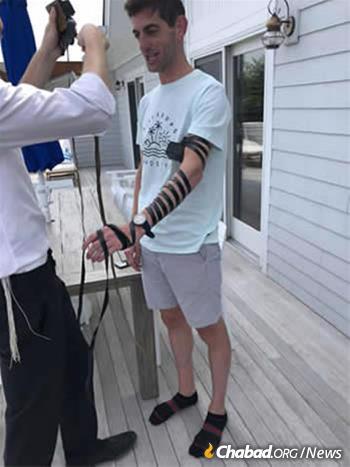 Banker Seth Binder wraps tefillin with Rabbi Aizik Baumgarten at Chabad of Montauk.