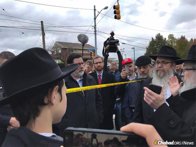 Rabbi Yisroel Rosenfeld (right), director of Chabad of Western Pennsylvania, speaks at a minchah prayer on Monday afternoon outside of Tree of Life, as Pittsburgh Mayor Bill Peduto looks on.