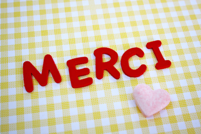 The word merci written in red on a tablecloth.