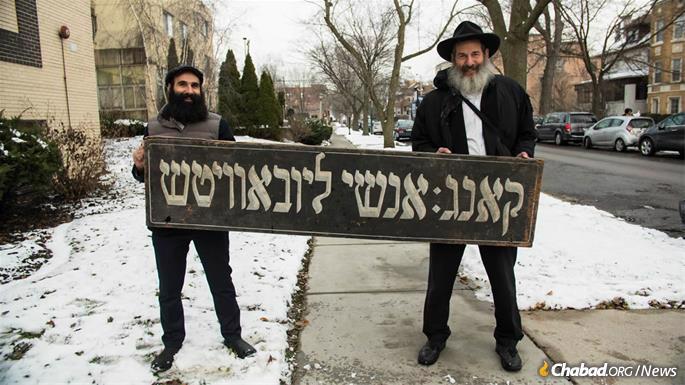 Menachem Posner and Dr. Lubin hold up a Yiddish sign of unknown vintage that once graced a previous location of Anshei Lubavitch. (Photo: Brett Walkow)