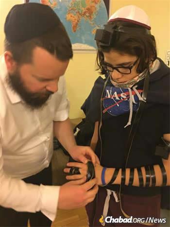 Yonatan Sebok, above, was the first boy to celebrate his bar mitzvah in Buda Castle Synagogue since 1686. Here, he puts on tefillin with Rabbi Asher Faith.