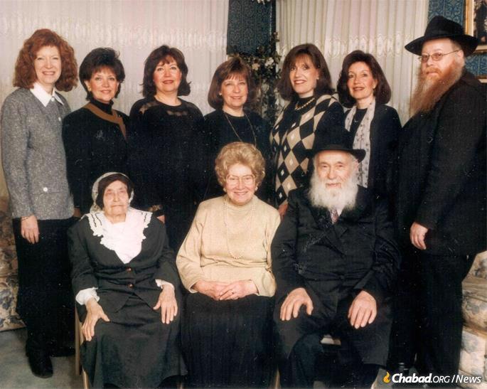 Shula Kazen sentada entre sua mãe e marido, com seus sete filhos.