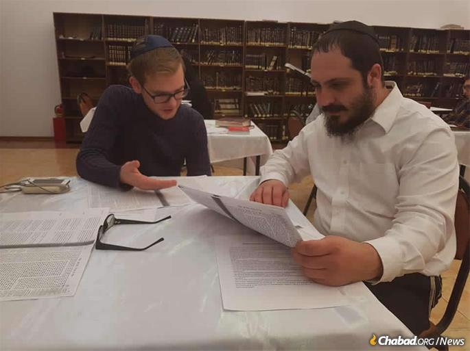 The rabbi studies Talmud with a local young adult.