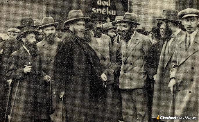 Rabbi Yosef Yitzchak (center, holding a cane, partially obscured) at the Riga train station circa 1930, speaking to Mordechai Dubin (in bowler hat with bowtie). The Rebbe&#39;s eldest son-in-law, Rabbi Shmaryahu Gourarie, is at center-left. (Photo: Rabbi Mordechai Glazman via Jewish Educational Media/Early Years)