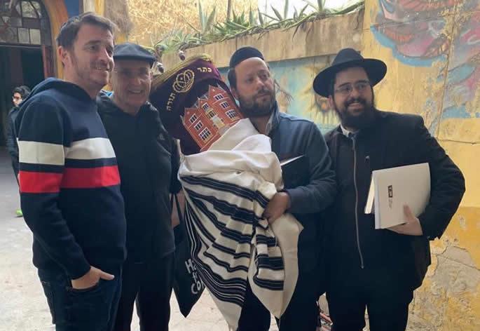 Rabbi Shneur Mizrahi, right, and community members return a Torah scroll to the synagogue.