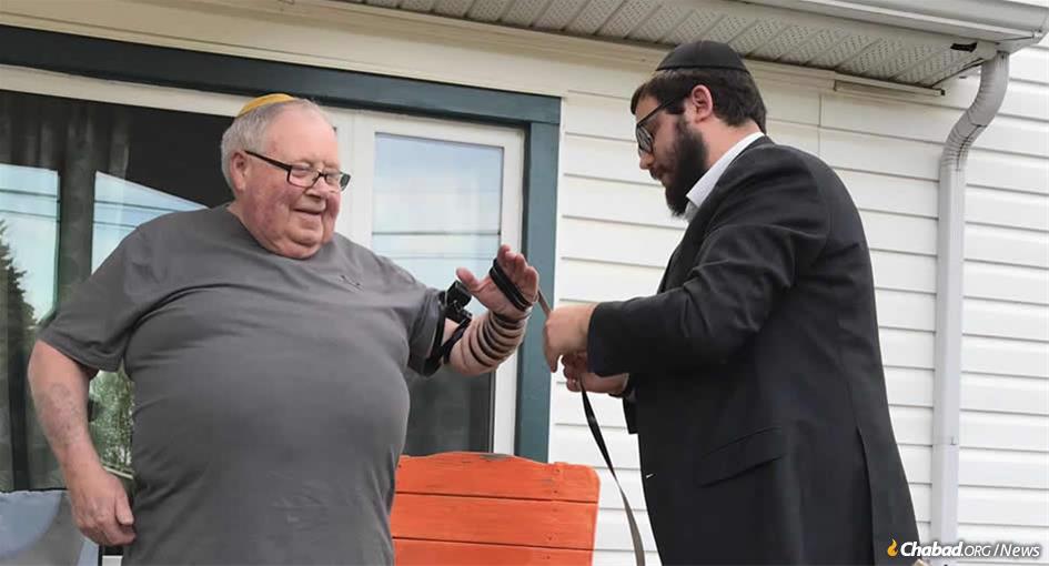 Rabbi Mendel Super helps Bob Friedman of North Battleford, Saskatchewan, Canada, put on tefillin.