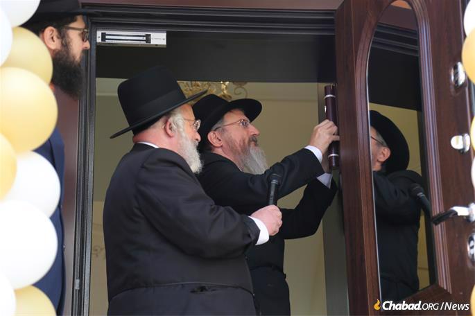 Lazar affixes the mezuzah, as others look on.