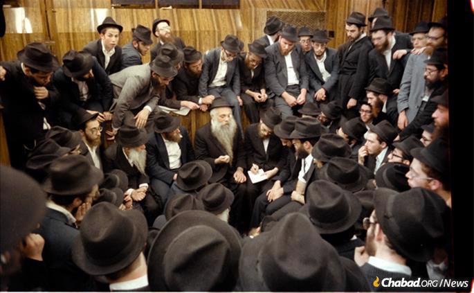 Chazarah, or repetition, following the Rebbe&#39;s farbrengen on Sept. 23, 1979. Rabbi Yoel Kahan is in the center, elucidating a point, while to his right, taking notes, is Rabbi Dovid Feldman, today chief editor of Lahak, which rendered the Rebbe&#39;s talks into Hebrew. Chazzarah took place in the synagogue and was open to everyone. (Photo: Jewish Educational Media/The Living Archive)