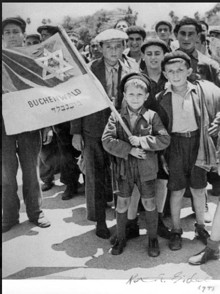Israel MeirLau no porto de Haifa, a caminho do campo de detenção de Atlit, segurando uma bandeira com outros sobreviventes de Buchenwald. Atrás da bandeira à esquerda - seu irmão Naftali (Foto: acervo YadVashem)