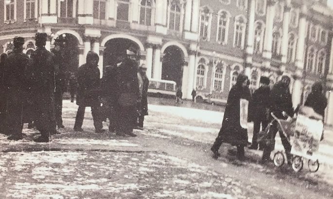 The beginning of the protest on Palace Square . Lev and Marina with the baby in the carriage with the 2 posters. Next to the Winter Palace, a bus is visible. It is waiting to take the family to the police station.