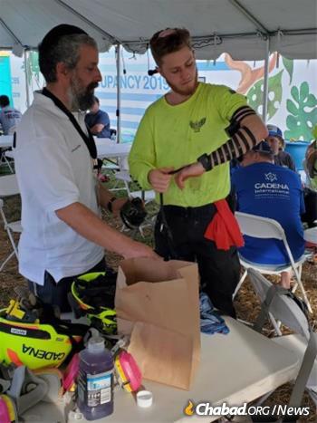 Rabbi Harlig assists a rescue and recovery volunteer from Mexico put on tefillin.