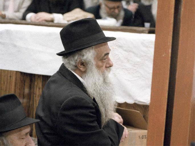 Rav Yoel HaKohen Kahn, appel&#233; simplement “Reb Yoel”, fut le transcripteur principal du Rabbi Mena’hem Mendel Schneerson, de m&#233;moire b&#233;nie, pendant plus de 40 ans. On le voit ici dans une pose famili&#232;re &#233;coutant le Rabbi enseigner lors du farbrenguen du 12 Tamouz 1983. (Photo: Jewish Educational Media/The Living Archive)