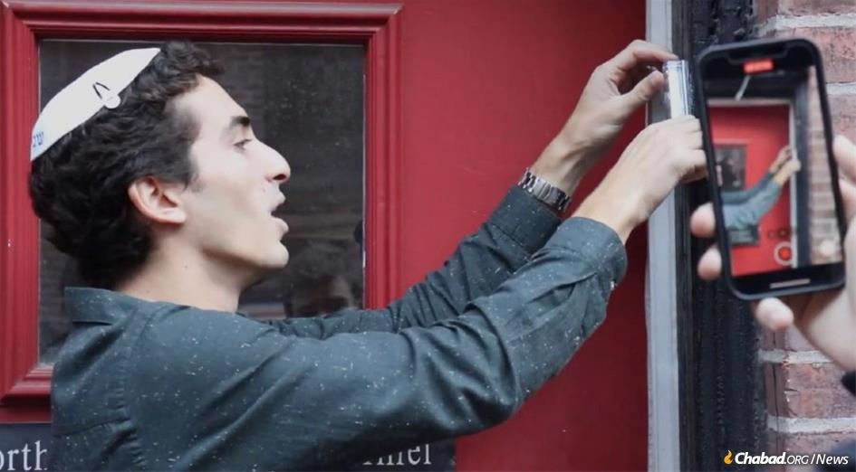 Eli Codron, a student at Northeastern University in Boston, replaces a mezuzah that had been torn down from outside a joint morning minyan hosted by Hillel and Chabad.