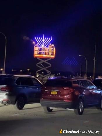 A menorah is hoisted 50 feet up in Port Washington on Long Island, N.Y., as thousands look on from their cars.