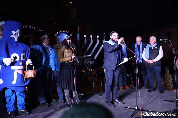 Rabbi Chaim Landa leads the lighting in St. Charles while his wife Bassy looks on.