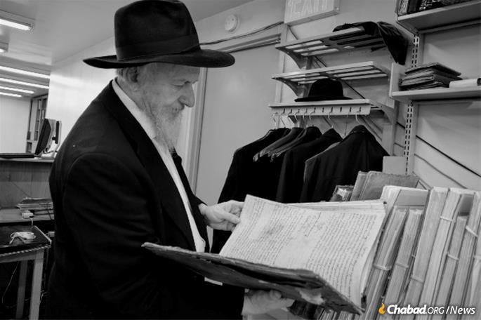 Head librarian Rabbi Shalom Ber Levine examines an old manuscript. (Photo: Mendel Super)