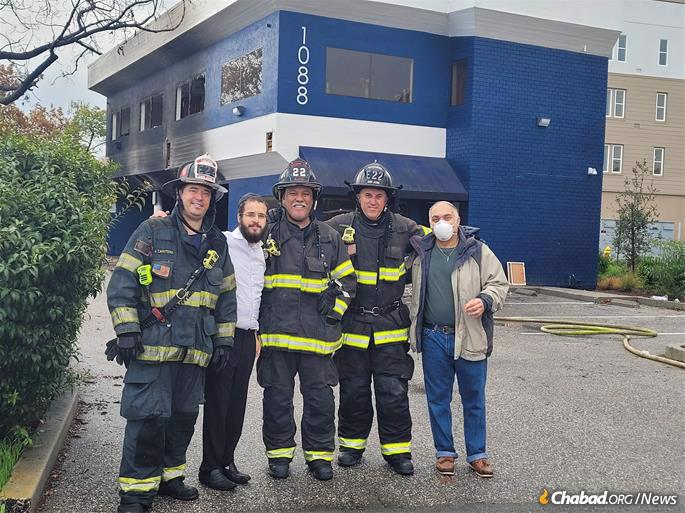 Rabbi Mendel Weinfeld, second from left, and community member Jacob Cohen, right, with firefighters