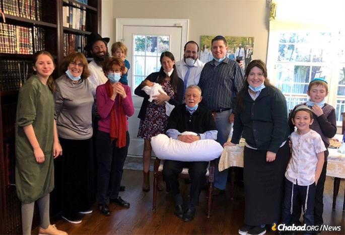 Rachele Kilgore with her newborn son, Shmuel. Her father, Richard Lipsky, seated, served as the sandek. He is surrounded by his family and the Bluming family.