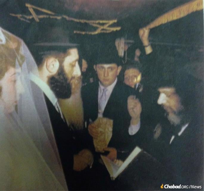 The Rebbe was mesader kiddushin at the wedding of Michel and Danya Raskin. Shlom Ber Raskin, center, looks on.