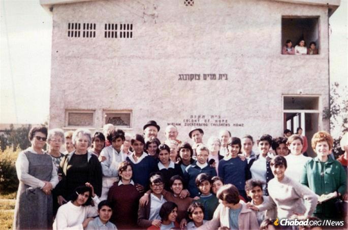 Rabbi and Rebbetzin Hecht with a group of children in front of the Miriam Zuckerberg Children's Home in the Colony of Hope that they founded. (Photo: Hecht Family)
