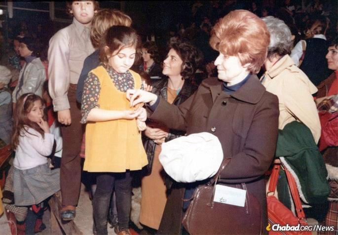 Distributing coins for charity at a children's rally in 770. (Photo: Hecht Family)