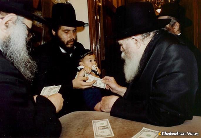 Rabbi Moskovitz and one of this children receive a dollar and a blessing from the Rebbe.