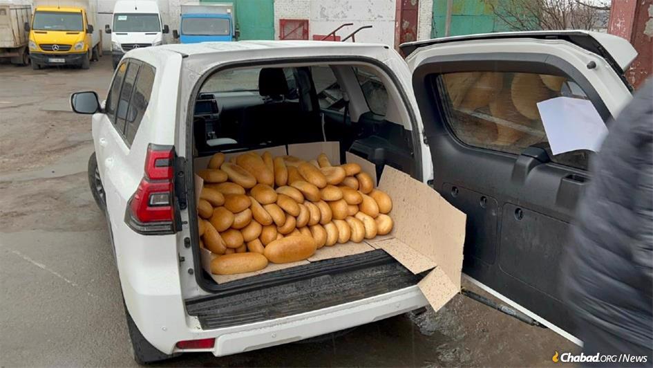 In Kherson, a worker fills Rabbi Yosef Yitzchak Wolff's car with bread.