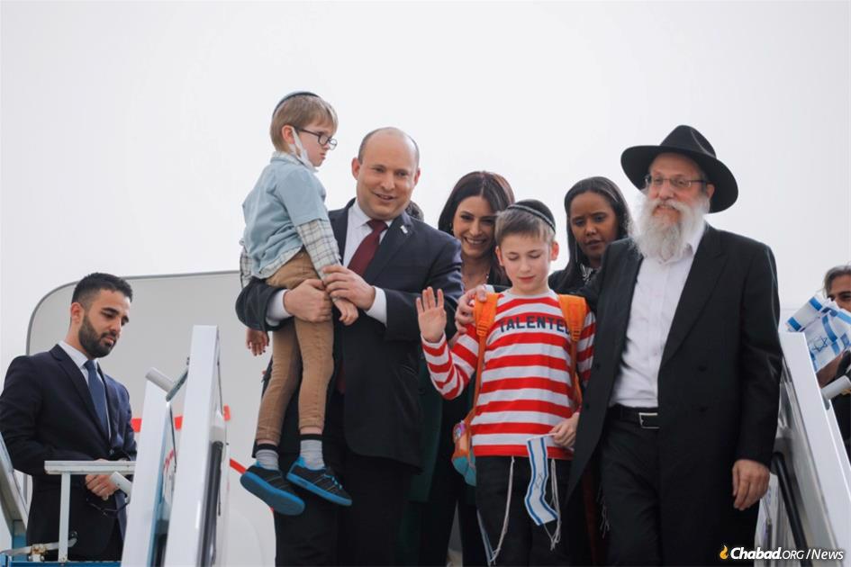 Prime Minister Naftali Bennett of Israel and Rabbi Shlomo Wilhelm of Zhitomir, Ukraine, with two of the 90 children who were evacuated from Zhitomir’s Chabad-run Alumim children’s home on Feb. 24. (Credit: Hadas Porush/Pool Photo)