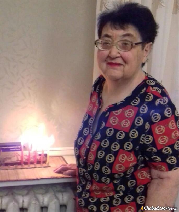 Valentina Levashina lights a menorah in her Mariupol home on Chanukah of 2021. Four months later, on March 28, she died in her hometown. Her daughter buried her in their apartment building's garden. Photo: Viktoria Levashina.