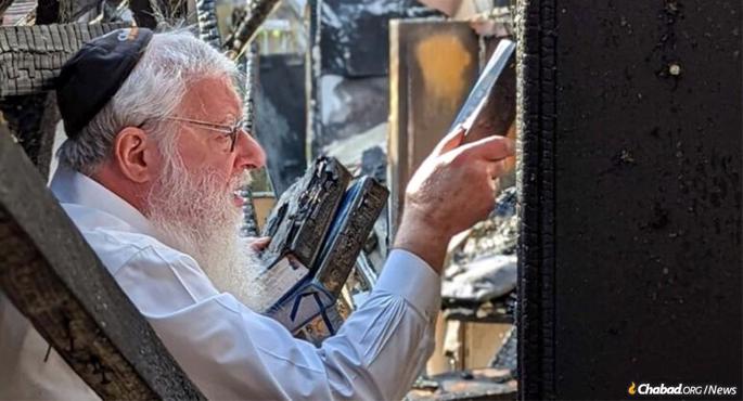 Rabbi Avrohom Litvin recovers holy books damaged in a fire that destroyed the Louisville, Ky., Chabad center.