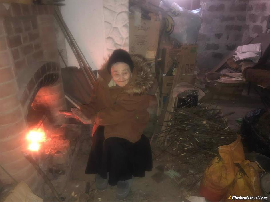 Elvira Bortz, 86, warms herself by a fire in a basement in Mariupol, Ukraine. Bortz, born in Mariupol, survived the Holocaust hidden in homes and a dug out. Following the onset of the current war in Ukraine, Bortz and her family were forced to shelter for 50 days before making it to Kiev. Photo: Bortz family.